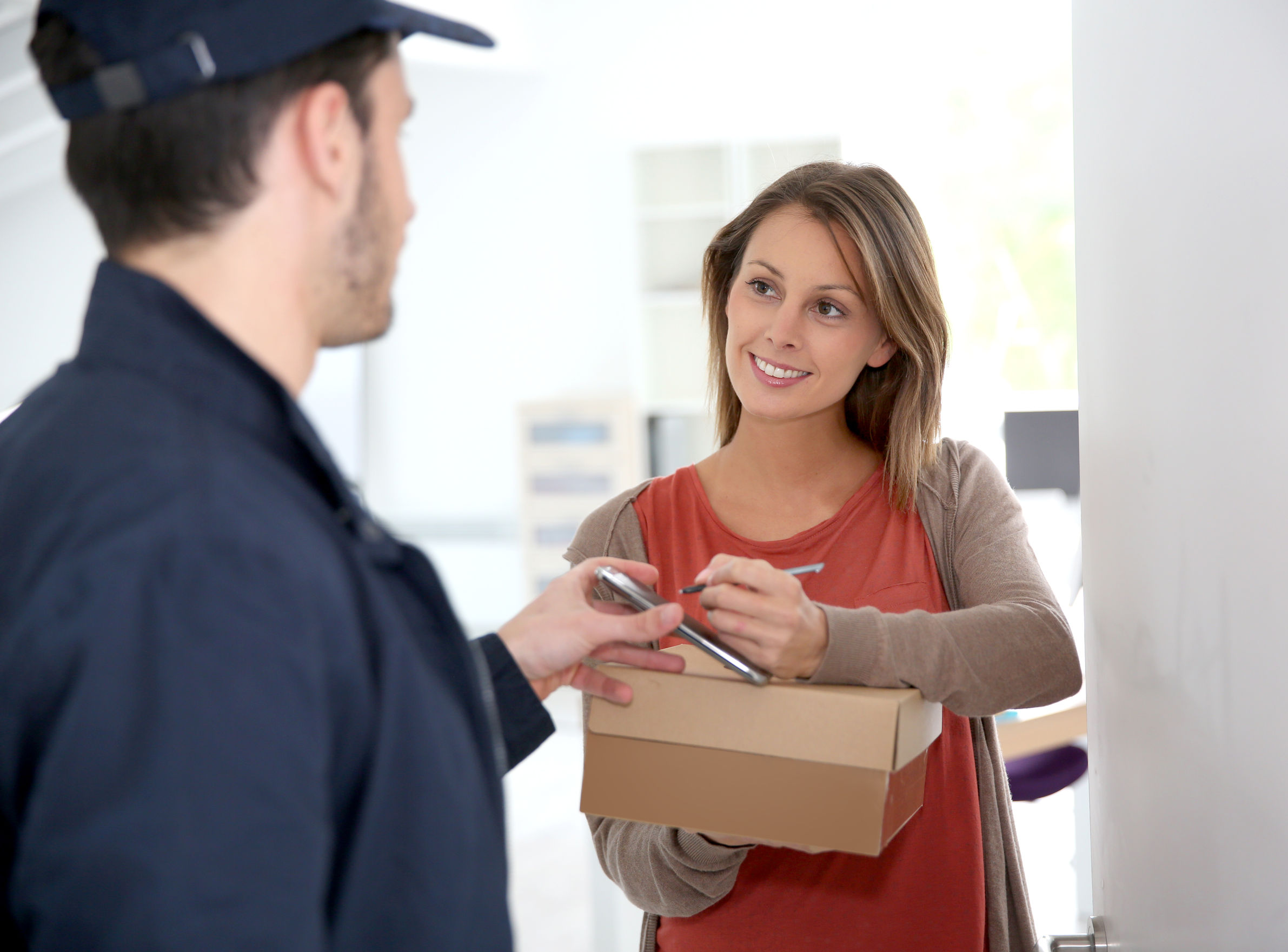 Woman signing to accept and receive her parcel from the carrier